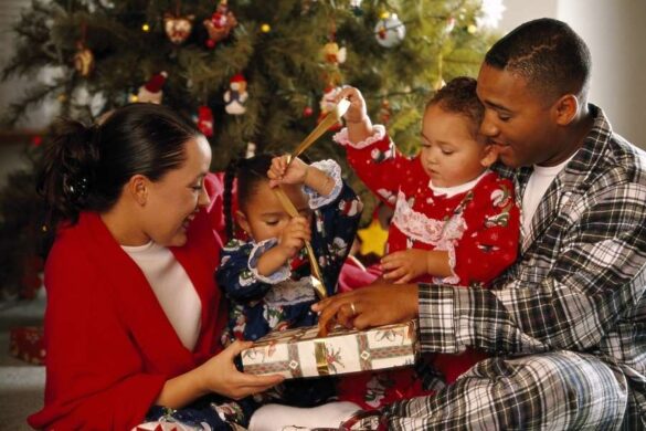 Happy family opening Christmas gift boxes together by decorated tree