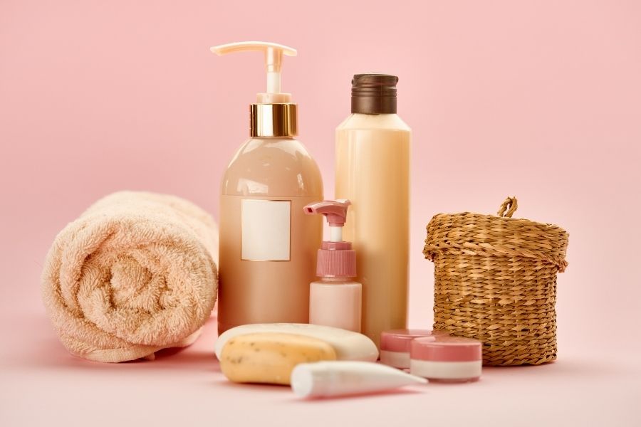 Revolutionary skincare products with natural soap, bottles, and wicker basket on pink background