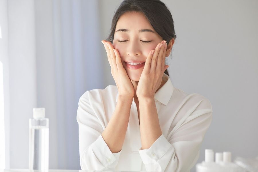 Woman applying Korean skincare product to face with gentle massage motions