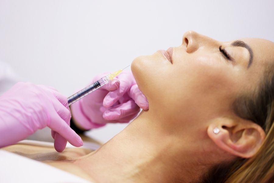 Professional administering cosmetic injection comparing Botox vs hyaluronic acid treatment options