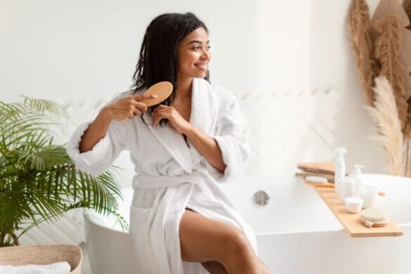 Woman in bathrobe brushing curly hair as part of curly hair routine