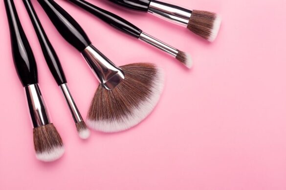 Professional makeup brushes with natural bristles arranged on pink background