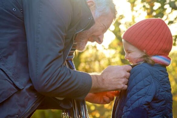 Father teaching child advanced scarf tying methods during golden hour outdoor moment