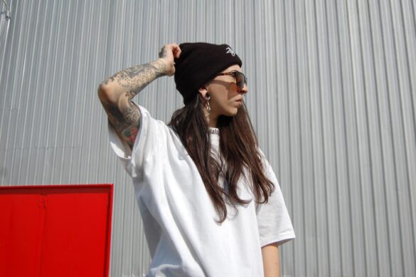 A woman in an oversized white t-shirt and black beanie, representing a popular streetwear clothing brand