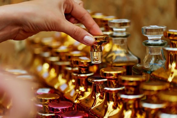 A hand carefully selecting a gold-capped fragrance bottle from a professional musk perfume distribution display