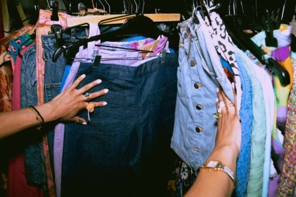 Hands sorting through colorful clothing on a rack to build a sustainable and Eco-Friendly Closet.
