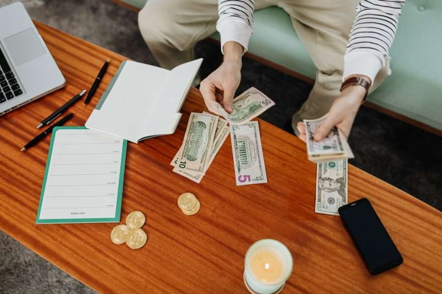 A person organizing finances and cash on a table when planning a budget-friendly floral arrangement